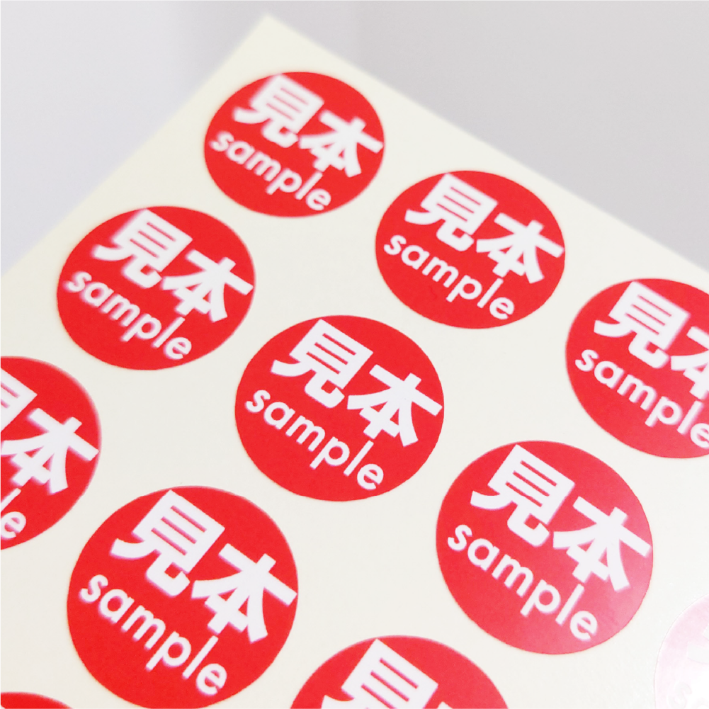 赤地に白文字で見本 sampleと表示された丸型シール